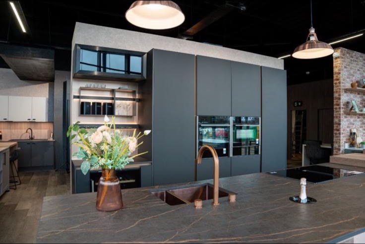 Dark grey kitchen island with a copper sink and tap