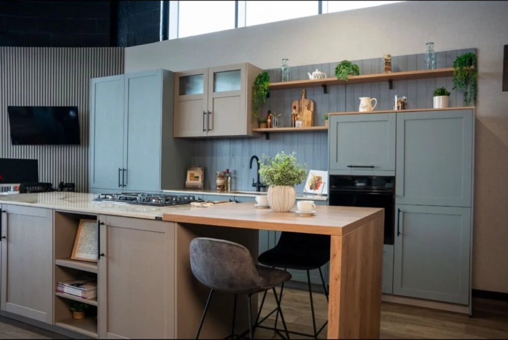 Light sage kitchen with oak shelving and a breakfast bar